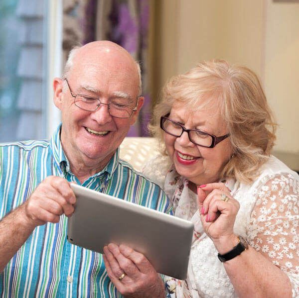 A couple engrossed in a tablet, sharing a moment of curiosity and discovery together. Wifi and internet facilities is available across our Anchor residency.