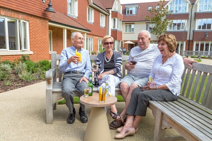 A group of residents gathered on a bench, sharing a moment of relaxation and camaraderie in the spacious green garden.