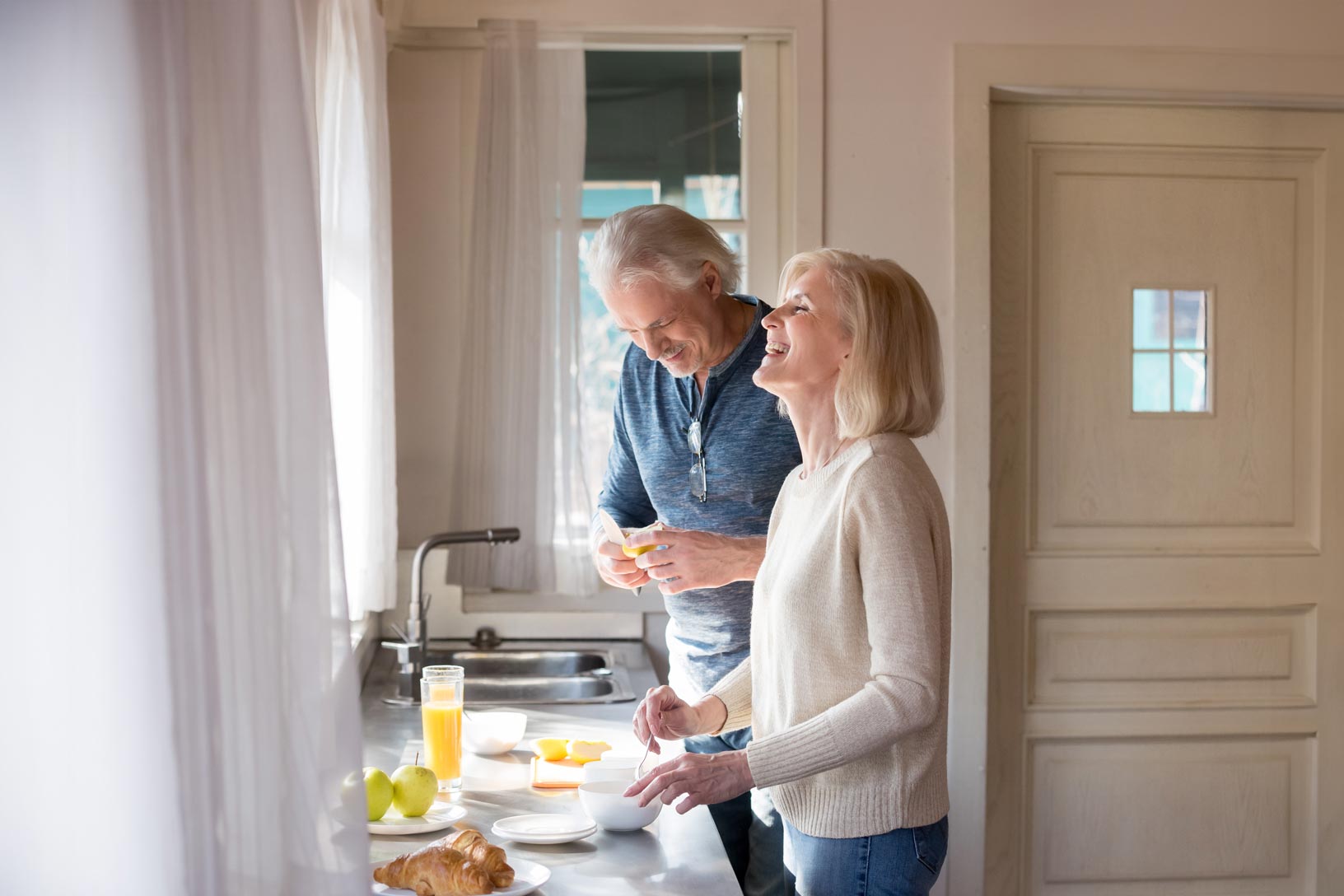 A couple enjoying their time in their spacious and bright kitchen making up breakfast.